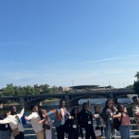 Group of students posing near Blue Bridge with arm opening